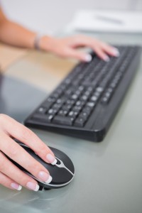 Hands using computer mouse and keyboard at office desk